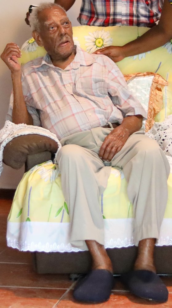 Walter Ferguson sentado en un sillón con cojines de flores.
